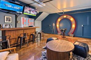 Eine Bar mit Holztresen, Barhocker, einem runden Tisch und einer Neonleuchtreklame.
