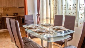 A dining area with a glass table and brown leather chairs. - Holiday apartment with air conditioning (Maružini)