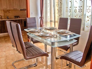 A dining area with a glass table and brown leather chairs. - Holiday apartment with air conditioning (Maružini)