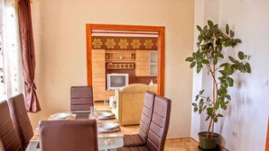A dining area with a table set for four, a television, and a potted plant. - Holiday apartment with air conditioning (Maružini)