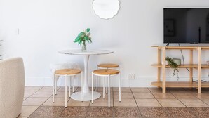 Un salon comprenant une table ronde, deux tabourets, un téléviseur et une étagère.