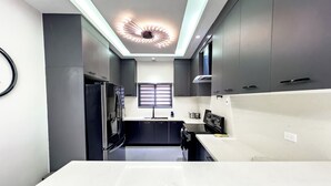 Une cuisine moderne dotée d’un îlot central, d’appareils électroménagers intégrés et d’un luminaire au plafond au design original.