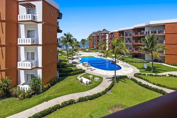 A hotel with a pool, palm trees, and a clear blue sky. - 320 - One Bedroom Ocean View, Vivo Resorts (Bajos de Chila)