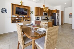 Una cocina moderna con armarios de madera, microondas integrado y refrigerador de acero inoxidable.