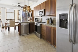 A modern kitchen with stainless steel appliances, wooden cabinets, and a dining area with a view. - 320 - One Bedroom Ocean View, Vivo Resorts (Bajos de Chila)