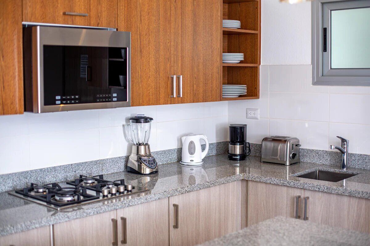 A modern kitchen with a built-in microwave, gas stove, blender, kettle, and toaster.