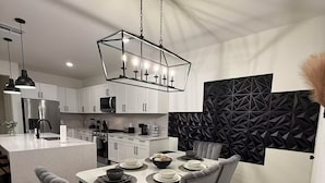 Een moderne keuken met witte kastjes, een centraal eiland en een eethoek met een tafel voor vier personen.