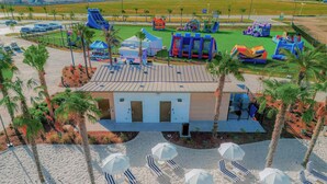 Een resort met een zwembad, strandparasols en een kinderspeelplaats.