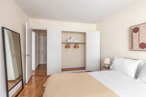 Ein Hotelzimmer mit Bett, Nachttisch mit Lampe, Kleiderschrank und Spiegel.