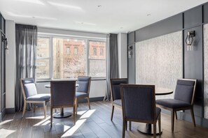 Ein modernes Hotelzimmer mit großem Fenster, rundem Tisch und vier Stühlen.