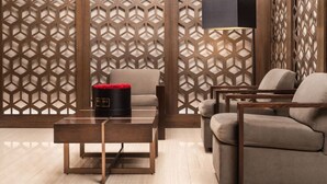 Ein modernes Wohnzimmer mit einer Wand im geometrischen Muster, einem Glastisch und zwei Sofas.