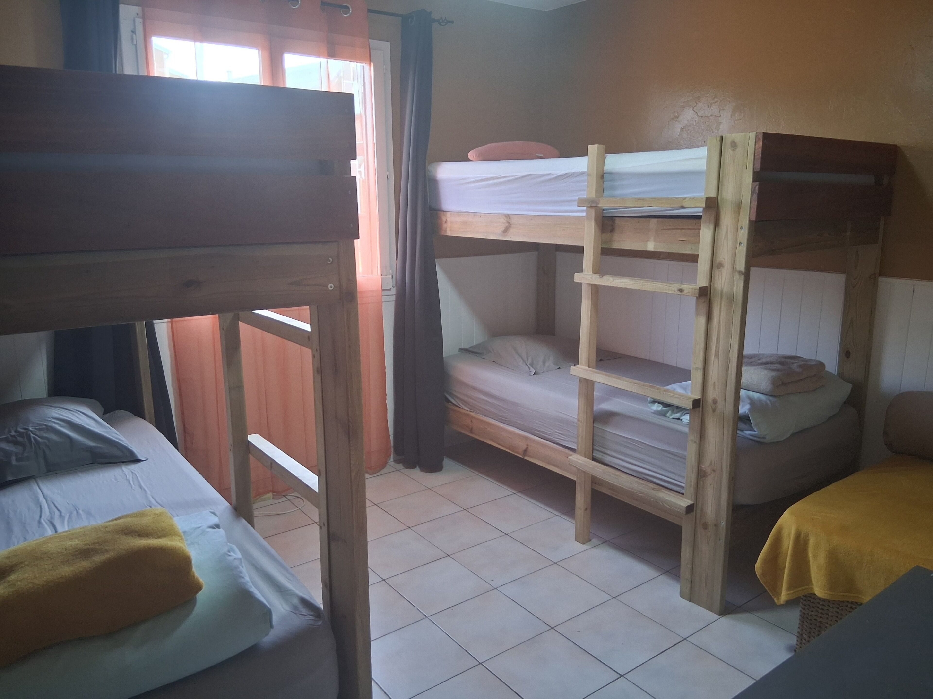 A dormitory room with bunk beds, a wooden ladder, and a yellow towel on one bed.