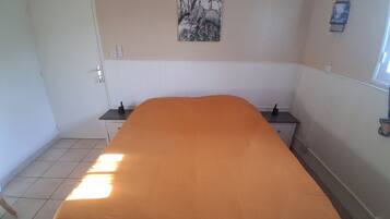 Ein Zimmer mit einem Bett, einem Nachttisch, einer Wandleuchte und einem Bild.