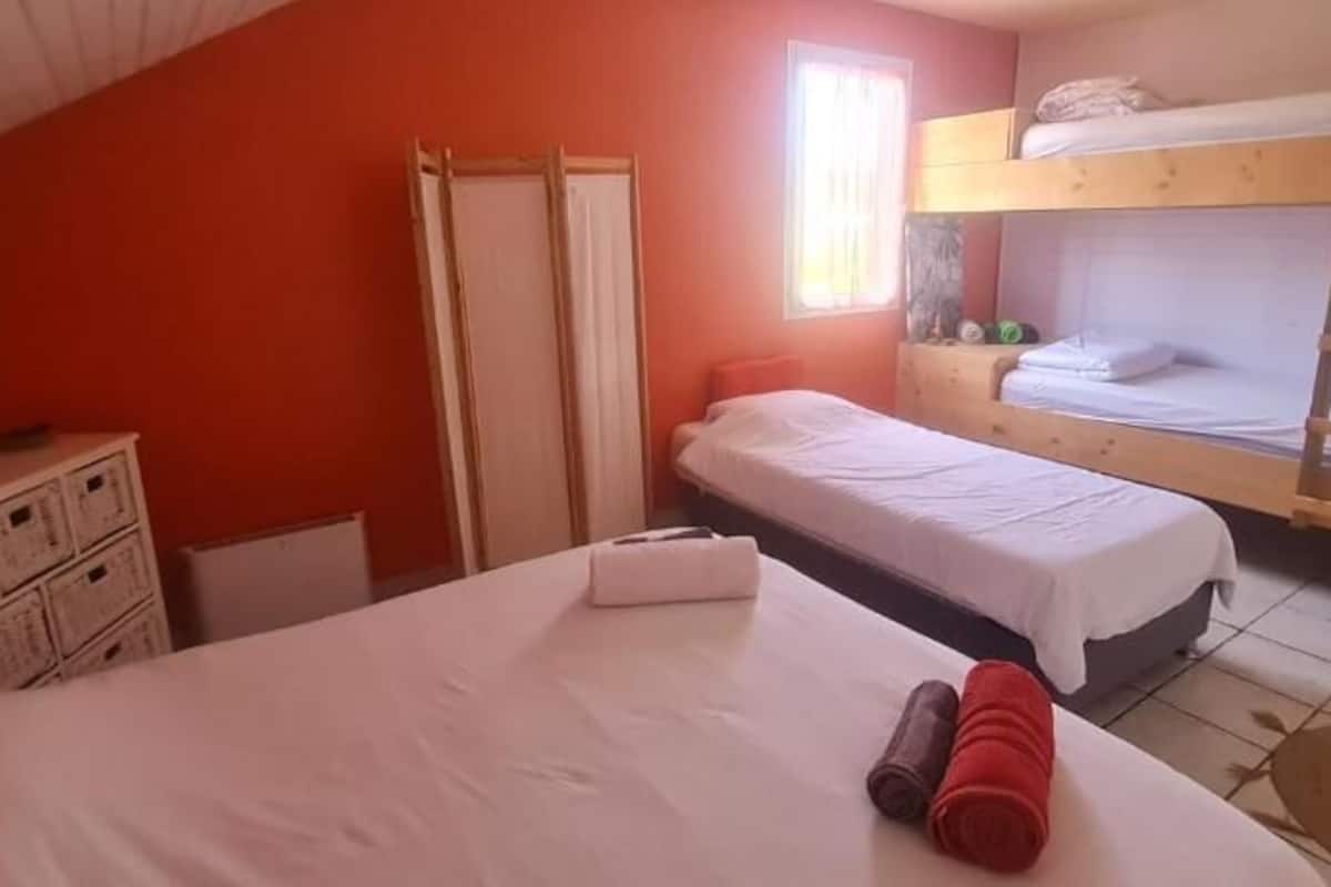 A dormitory room with two single beds, a wardrobe, and a desk.