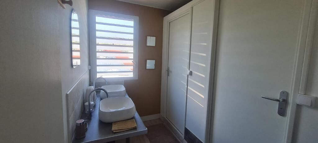 A small bathroom with a sink, a towel, and a window with blinds.