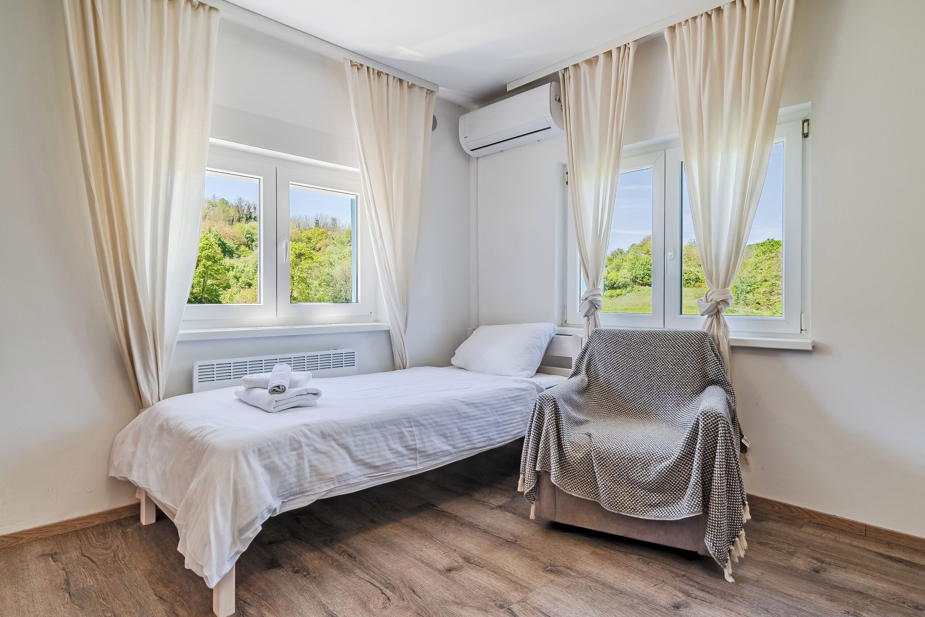 Ein Schlafzimmer mit einem Einzelbett, einem Sessel und einer Klimaanlage.