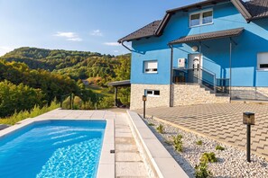 A blue building with a swimming pool and a view of a forested hillside. - The Blue House with Sauna & Jacuzzi, Desinić, Croatia (Desinić)