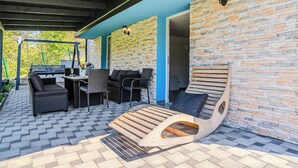 An outdoor patio with a stone wall, a wooden lounge chair, and outdoor furniture. - The Blue House with Sauna & Jacuzzi, Desinić, Croatia (Desinić)
