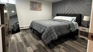 A modern bedroom with a bed, bedside table, and a wall-mounted artwork. - Cozy Home. (Hempstead)