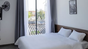 A modern hotel room with a large bed, a ceiling fan, and a view of the cityscape through the window. - Khánh Vy Hotel (Hue)