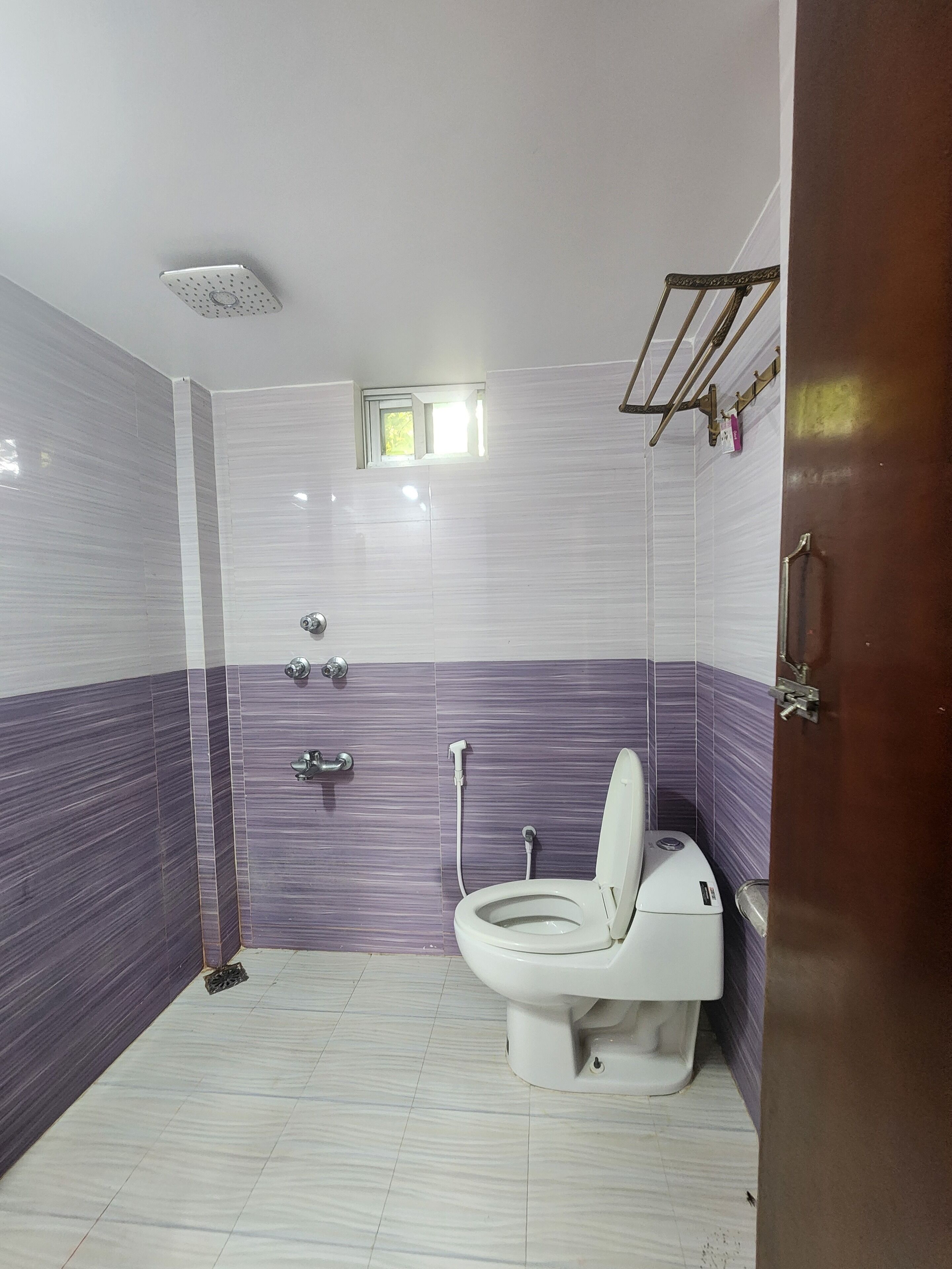 Un baño con inodoro, ducha y una ventana pequeña.
