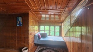 A small, cozy room with wooden walls and ceiling, a bed with pillows, a window, and a rug. - Labah Tong Hill Resort Bandarban (Bandarban)