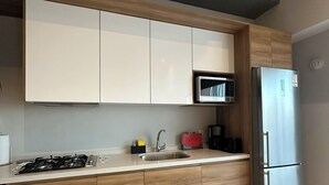 Una cucina moderna con mobili bianchi, un frigorifero in acciaio inossidabile, un forno a microonde e un piano cottura a gas.