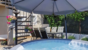 An outdoor hot tub with a table and chairs under a large umbrella, surrounded by potted plants and a staircase. - Apartment L&V by Interhome (Pula/Galižana)