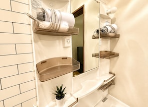 A bathroom with a white tiled wall, a mirror, a hairdryer, and a shelf with toiletries. - [Tsubame no Ie Imazato] Luxurious Japanese-Modern Entire House Rental | 3 min to Shin-Fukae | 5 min to Imazato | 12 min to Namba by train | Fully renovated in 2026 | Popular with families with children (Oimazato-minami, Higashinari-ku, Osaka-shi)
