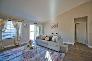 A living room with a sofa, coffee table, and a door leading to another room.