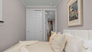 A bedroom with a white bed, beige bedding, and a framed picture on the wall. - Spacious Midtown Retreat 2BR NYC Haven (New York)