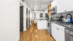 A modern kitchen with white cabinets, stainless steel appliances, and a wooden floor. - Prime NYC Location 4BR Spacious Haven (New York)