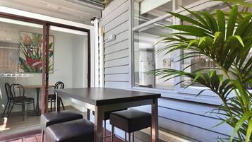 A dining area with a table and chairs, a glass door leading to a room, and a potted plant.