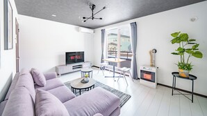 Ett modernt vardagsrum med en soffa, en tv, en öppen spis och en balkong med gardiner.