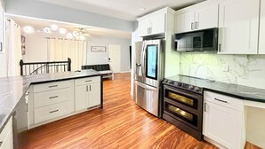A modern kitchen with white cabinetry, stainless steel appliances, and a marble backsplash.