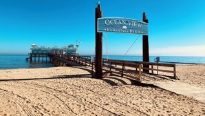 A wooden pier leading to a dock with a sign reading "Ocean View Fishing Pier." - New, Walk to Beach, Game Room, Fire Pit, King Beds (Norfolk)