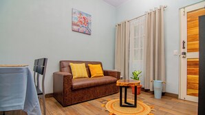 A living room with a brown leather sofa, a small wooden table, a potted plant, and a patterned rug. - Villa Mali Arenal La Fortuna La Fortuna Costa Rica Jacuzzi Area (Provincia de Alajuela)