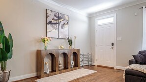 A modern living room with a wooden console table, a large abstract painting, and a potted plant.