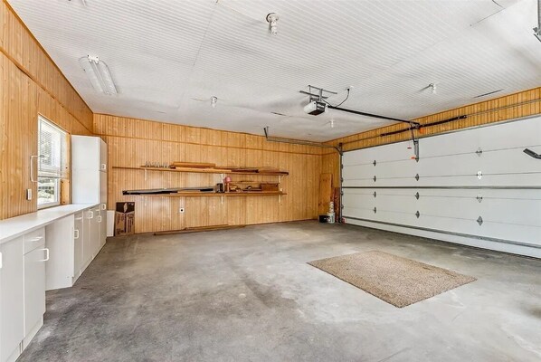 A garage with wooden walls, a concrete floor, and a white garage door. - Spacious & Cozy Mountain House in Fairplay (Fairplay)