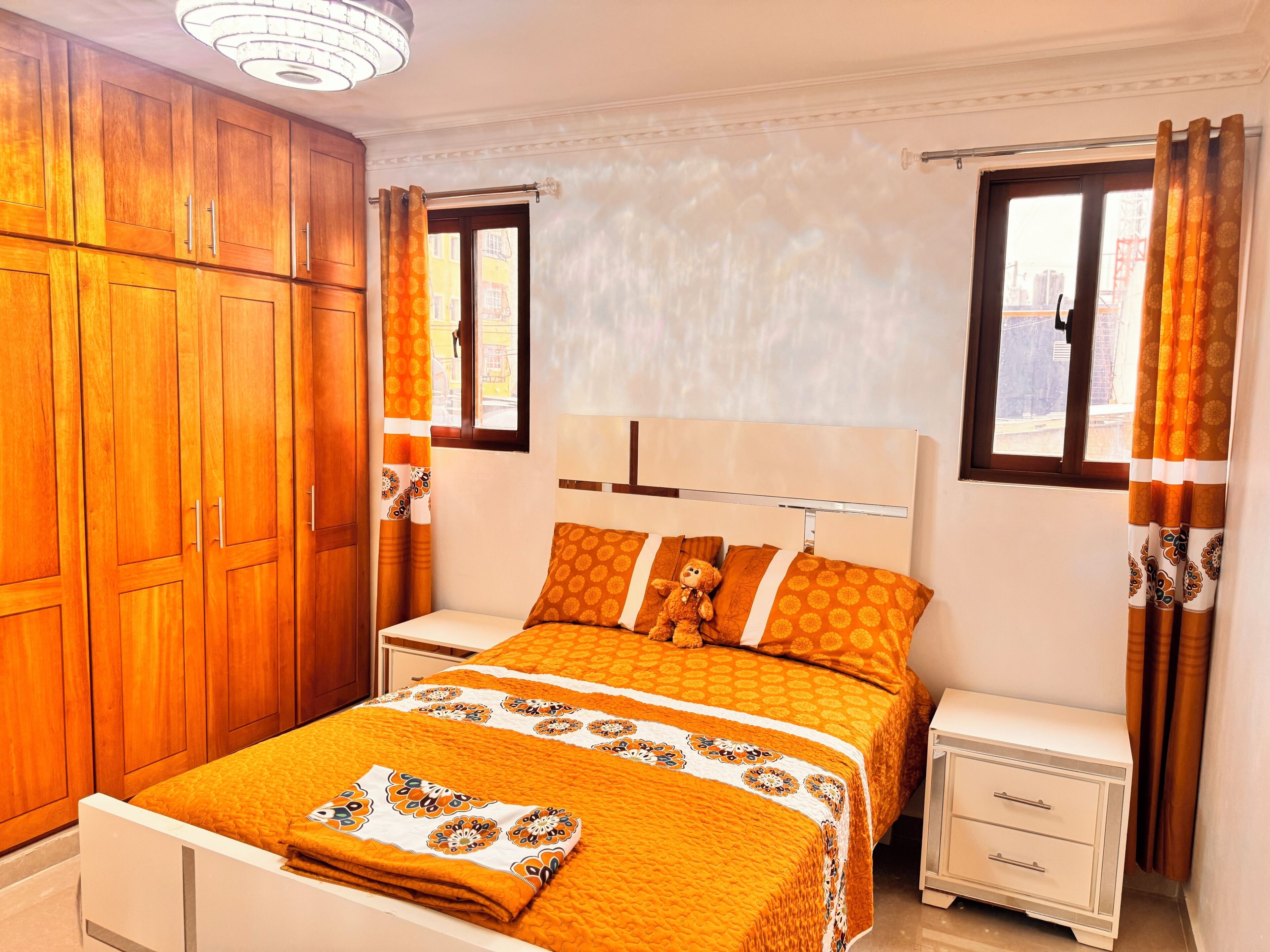 A bedroom with a bed, nightstands, and wooden cabinets.