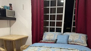 Ein Schlafzimmer mit einem Bett, einem Holztisch und einem Fenster mit Vorhängen.