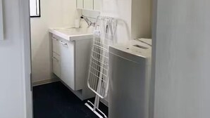 Une salle de bain moderne et compacte, dotée d’un lavabo blanc, d’un miroir et d’un grand chauffe-eau cylindrique.