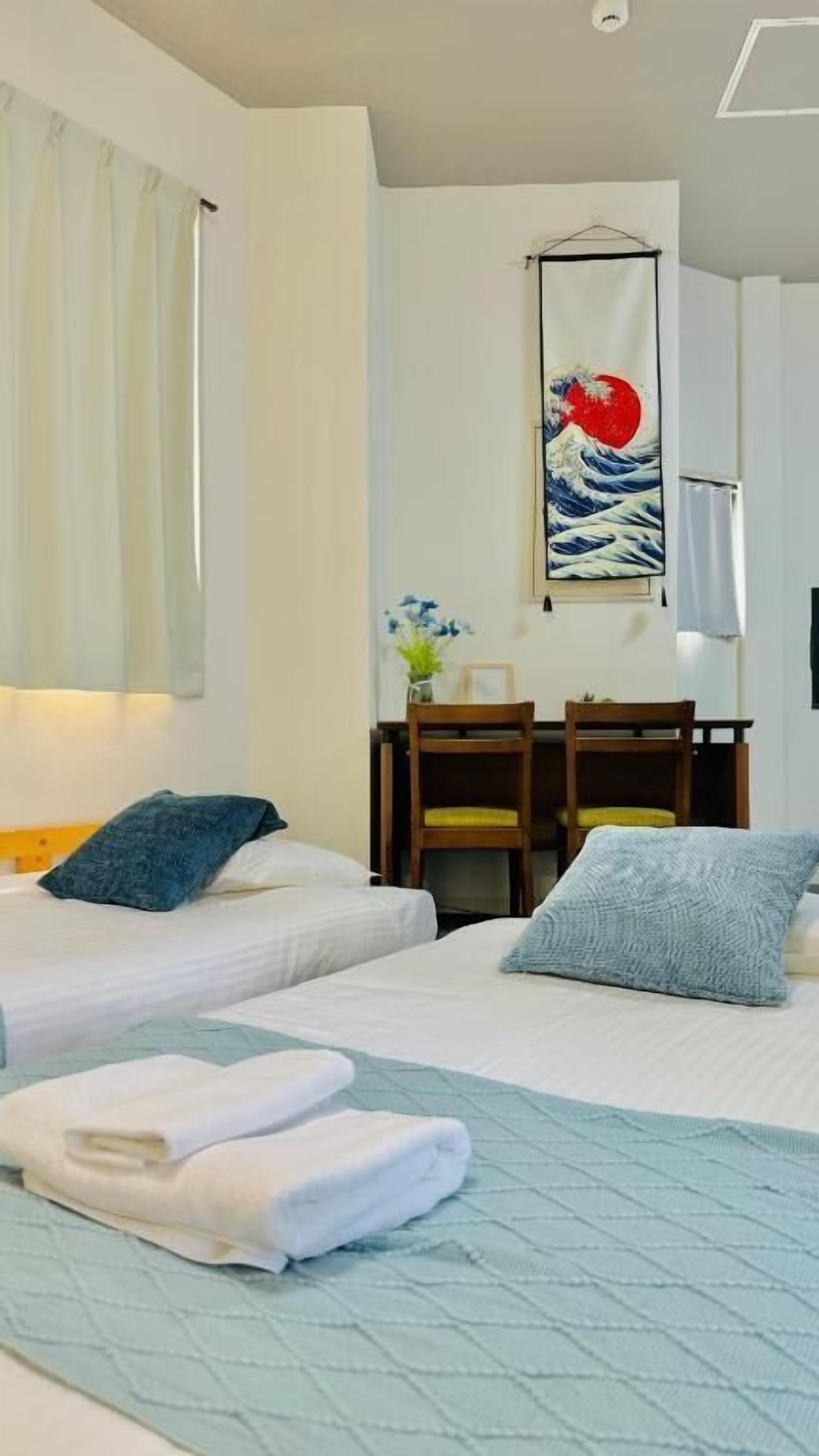 A hotel room with two beds, a desk, and a wall-mounted artwork.