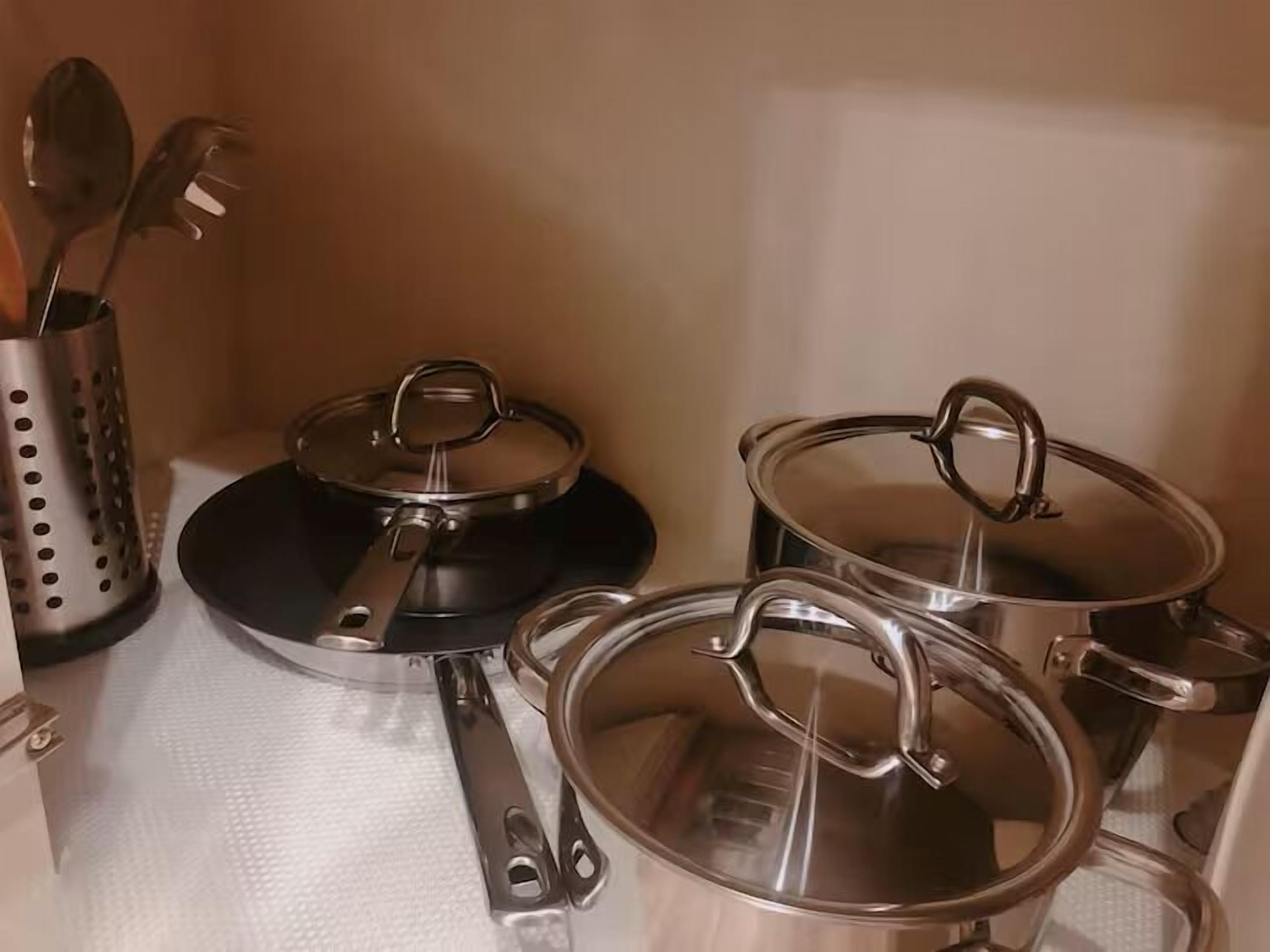 A kitchen with stainless steel pots and pans on a countertop.
