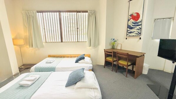 Een hotelkamer met twee bedden, een bureau, een stoel, een televisie en een raam met gordijnen.