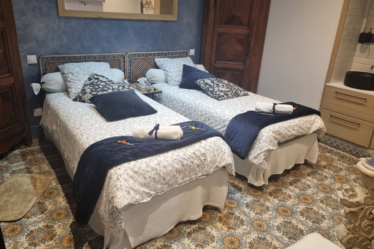 Un lit double avec une couvre-lit à motifs floraux, une tête de lit en bois et une table de chevet avec une lampe.