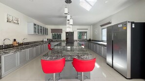 Une cuisine moderne dotée d’un îlot central, d’appareils électroménagers en acier inoxydable et de tabourets de bar rouges.