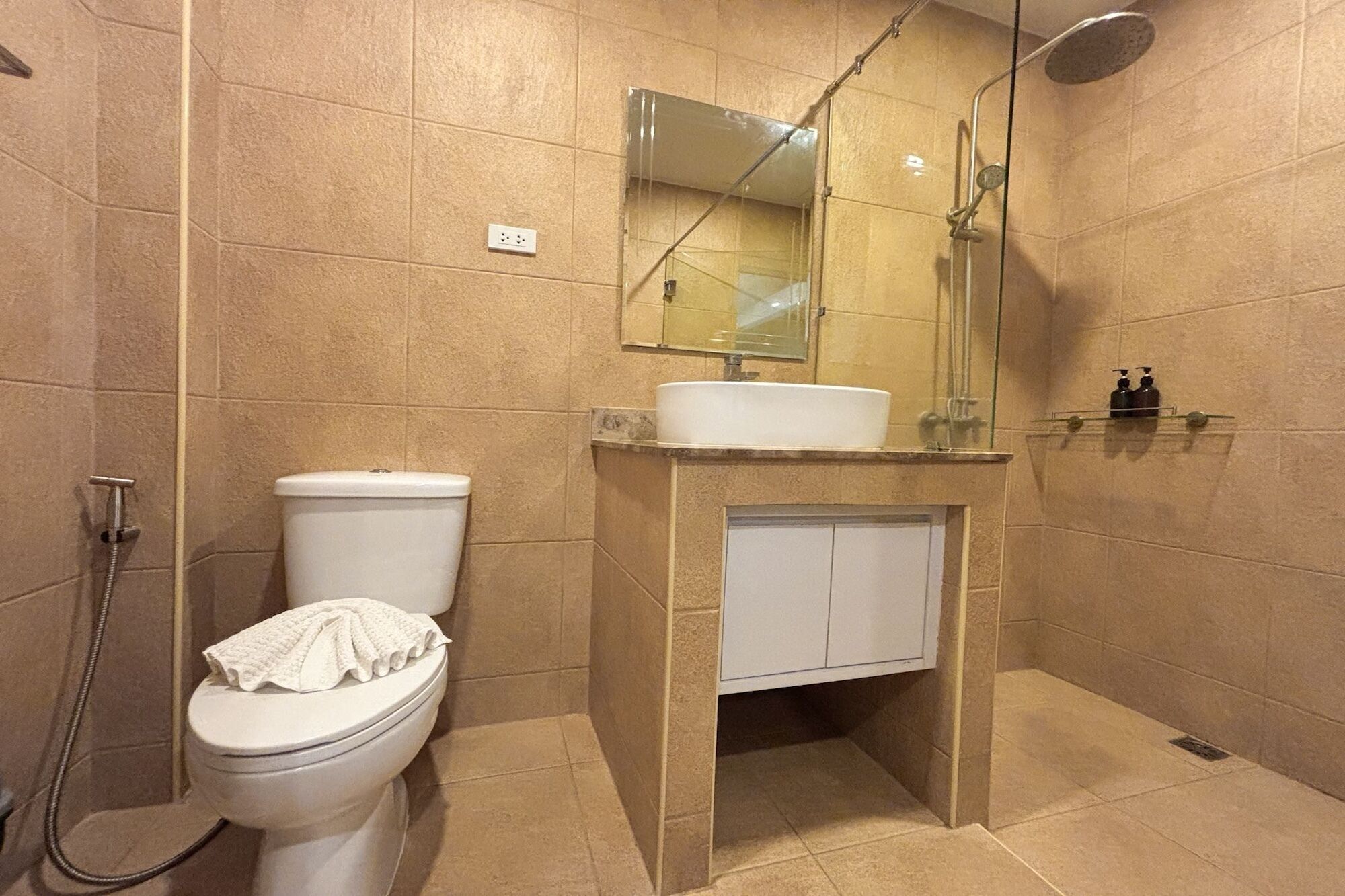 A bathroom with a toilet, a sink with a mirror above it, and a shower area.