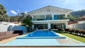 Une maison moderne à deux étages avec une piscine située dans le jardin avant.