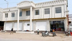 Un edificio a due piani con un'ampia porta garage, un'indicazione per i servizi igienici e una vetrina con il cartello che recita "HOTEL & FUNSHIP PARADISE".